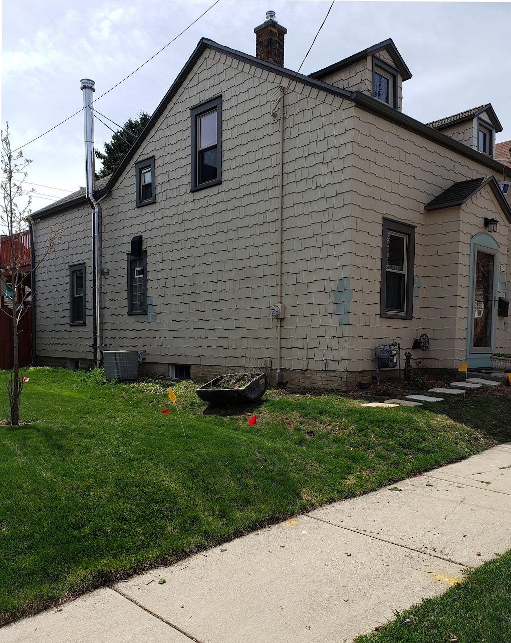 Before: Full exterior: weathered cedar A-frame repainted a rich brown