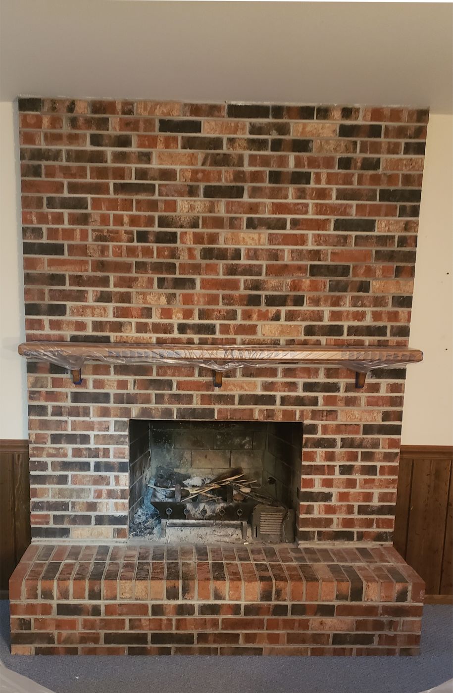 Before: Brick fireplace painted a soft gray, with wood paneling painted white
